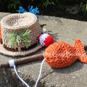 May include: A crocheted fishing hat with colorful yarn accents and a crocheted fish on a stick. The Cozy Buckeye is written on the stick.