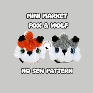 May include: Two crocheted plush toys, a fox and a wolf, with large eyes and white accents. The text reads MINI MARKET FOX & WOLF and NO SEW PATTERN, with a small logo in the center featuring a bird and the text The Cozy Buckeye.