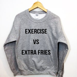 Puede incluir: Una sudadera gris con el texto "EXERCISE VS EXTRA FRIES" impreso en negro.