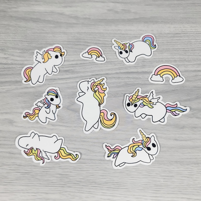 May include: A collection of white unicorn stickers with colorful manes and tails, along with two rainbow stickers. The unicorns are in various poses, some with wings. The stickers have a black outline.