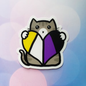 May include: A gray cat holding a heart-shaped sticker with the colors of the non-binary pride flag: yellow, white, purple, and black.