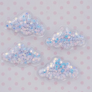 May include: Four clear plastic cloud-shaped embellishments filled with iridescent star-shaped glitter.