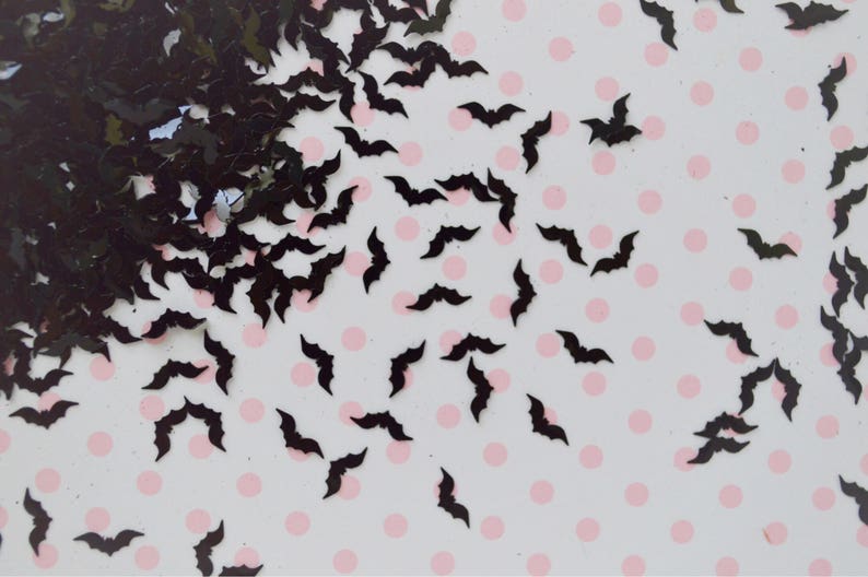 May include: Black bat cutouts scattered on a white background with pink polka dots.