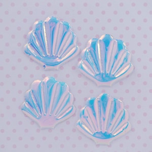 May include: Four iridescent blue seashell shaped embellishments with a white background.
