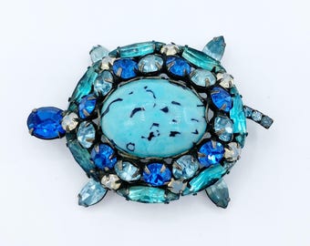 May include: A turquoise and blue jeweled turtle brooch. The turtle's shell is made of a turquoise cabochon surrounded by blue and turquoise rhinestones.