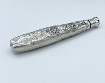 May include: A silver, hammered, and engraved, decorative bottle stopper with a floral design.