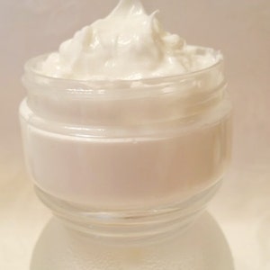 May include: A glass jar filled with a white, creamy moisturizer. The jar is labeled "Pampered Skin Care".