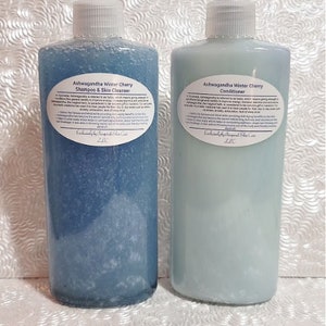 May include: Two blue plastic bottles with white labels. The labels have text that reads "Ashwagandha Winter Cherry Shampoo & Skin Cleanser" and "Ashwagandha Winter Cherry Conditioner".