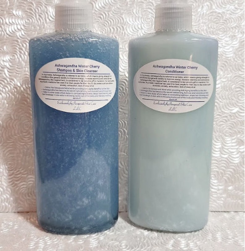 May include: Two blue plastic bottles with white labels. The labels have text that reads "Ashwagandha Winter Cherry Shampoo & Skin Cleanser" and "Ashwagandha Winter Cherry Conditioner".