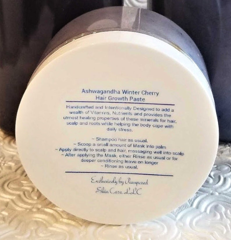 Puede incluir: Tarro blanco con tapa negra etiquetado como "Ashwagandha Winter Cherry Hair Growth Paste". La etiqueta incluye instrucciones para usar la pasta como mascarilla para el cabello o acondicionador sin enjuague. La etiqueta tambi&eacute;n dice "Exclusively by Pampered Skin Care LLC."