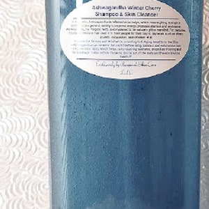 May include: A blue plastic bottle with a white label that reads "Ashwagandha Winter Cherry Shampoo & Skin Cleanser" and "Exclusively by Peaceful Skin Care".