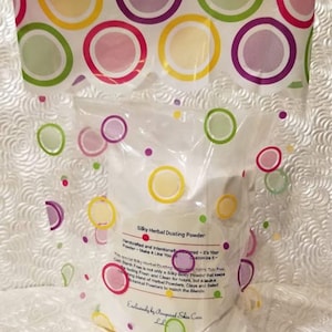 May include: A white plastic bag with a label that reads "Silky Herbal Dusting Powder" and "Handcrafted and Intentional - It's Your Powder - Make It Like You Customize It". The bag is decorated with colorful circles.