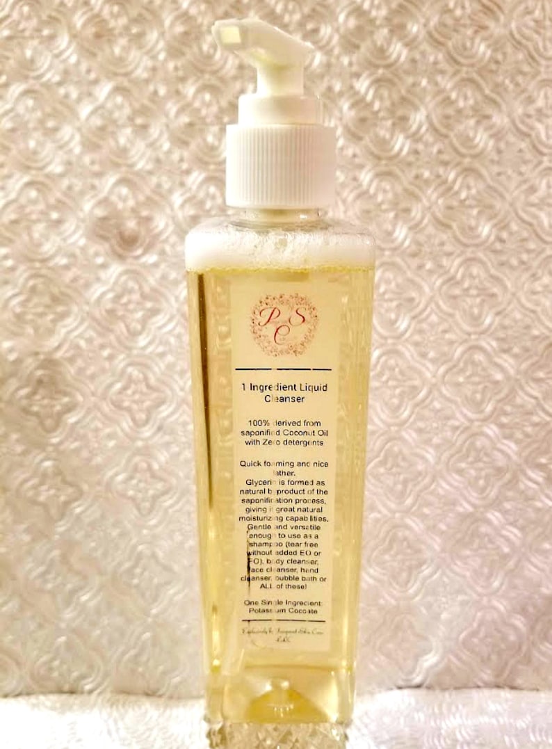 May include: A clear plastic bottle with a white pump dispenser filled with a yellow liquid. The bottle label reads "1 Ingredient Liquid Cleanser" and lists the ingredients as 100% derived from saponified Coconut Oil with Zero detergents. The label also describes the product as quick foaming and nice lather, with Glycerin formed as a natural byproduct of the saponification process, giving it great natural moisturizing capabilities. The label also states that the product is gentle and versatile enough to use as a shampoo, body cleanser, face cleanser, bubble bath, or all of these. The label also states that the product contains one single ingredient: Potassium Cocoate.