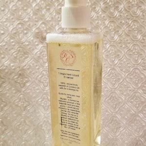 May include: A clear plastic bottle with a white pump dispenser filled with a yellow liquid. The bottle label reads "1 Ingredient Liquid Cleanser" and lists the ingredients as "100% derived from saponified Coconut Oil with Zero detergents".