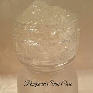 Pode incluir: Um frasco de vidro transparente cheio de um gel espesso e transl&uacute;cido. O frasco tem uma superf&iacute;cie texturizada e o texto "Pampered Skin Care" est&aacute; impresso na parte inferior.
