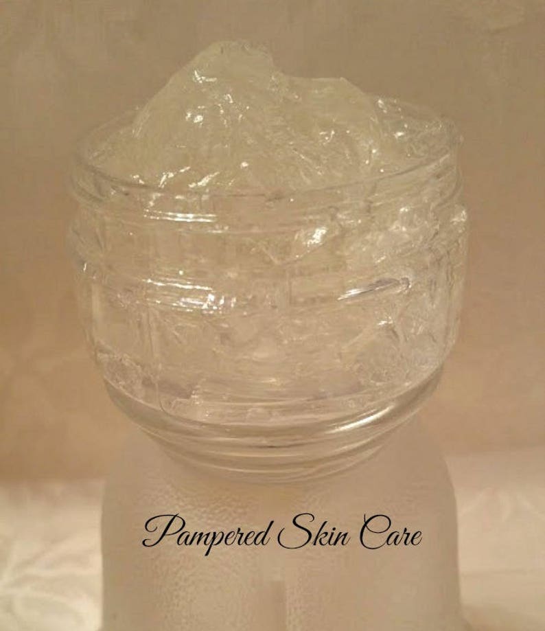 Pode incluir: Um frasco de vidro transparente cheio de um gel espesso e transl&uacute;cido. O frasco tem uma superf&iacute;cie texturizada e o texto "Pampered Skin Care" est&aacute; impresso na parte inferior.