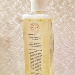 May include: A clear plastic bottle with a white pump dispenser filled with a yellow liquid. The bottle label reads "1 Ingredient Liquid Cleanser" and lists the ingredients as "100% derived from saponified Coconut Oil with Zero detergents".