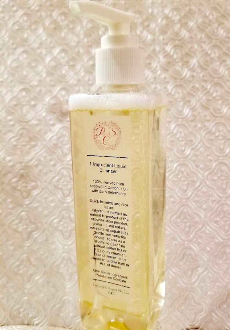 May include: A clear plastic bottle with a white pump dispenser filled with a yellow liquid. The bottle label reads "1 Ingredient Liquid Cleanser" and lists the ingredients as "100% derived from saponified Coconut Oil with Zero detergents".