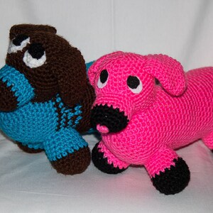 May include: Two crocheted stuffed animals, one brown and blue and one pink with black accents.