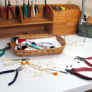 Making jewelry at the workbench with tools and gemstones.