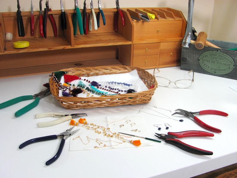 Making jewelry at the workbench with tools and gemstones.