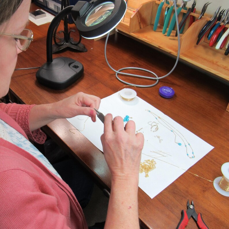 Making jewelry at the workbench with tools and gemstones.