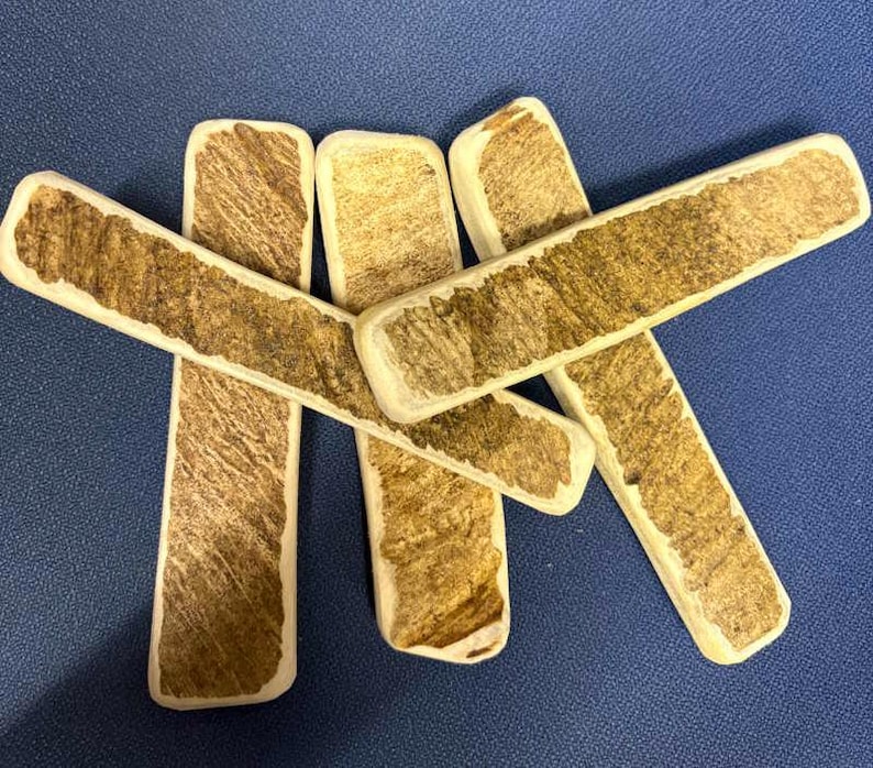 May include: Five rectangular sticks with a smooth, light-colored border and a textured, brown, wood-like center. The sticks are arranged in a crisscross pattern, showcasing a natural, fibrous appearance on the surface of each individual piece.