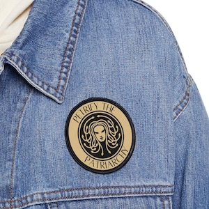 May include: A denim jacket with a gold and black circular patch that says "Petrify the Patriarchy" with a black and white illustration of a woman with snakes for hair.