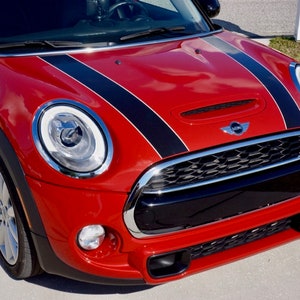 May include: A red Mini Cooper S with black racing stripes on the hood. The car has a black grille with a chrome surround and a chrome Mini logo. The car has a black front bumper with a silver S badge.