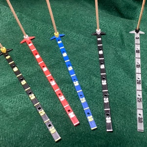 May include: Five measuring sticks with different colored scales. The scales are marked with numbers from 5 to 30. The sticks are made of wood and have a metal tip.