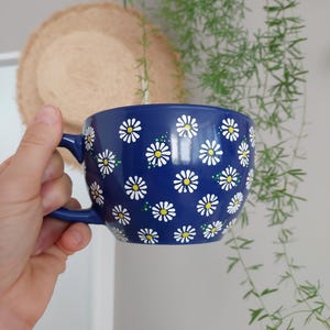 Close-up of the daisy pattern showing yellow centers and green leaves against the navy background