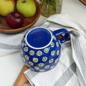 Close-up of the daisy mug handle and the white floral pattern against the navy background