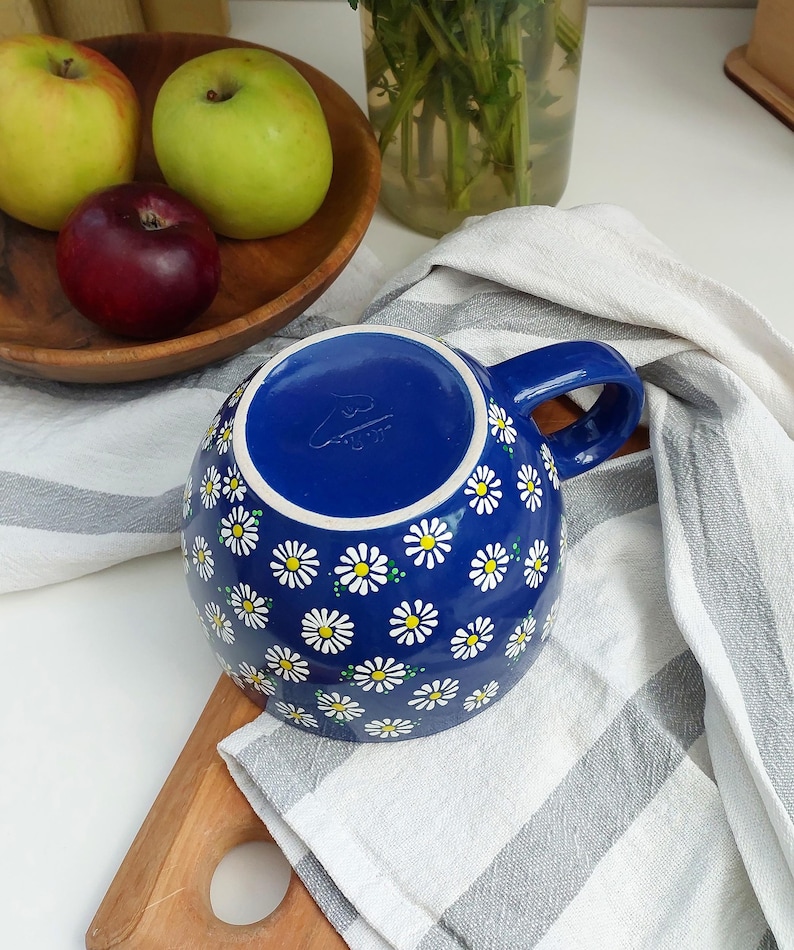 Close-up of the daisy mug handle and the white floral pattern against the navy background