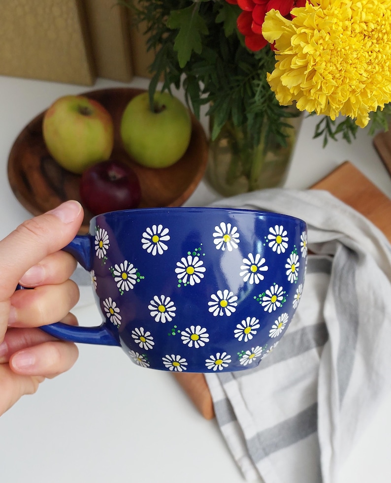 Navy blue ceramic daisy mug, front view showing the rounded shape and white daisy pattern
