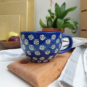 Daisy mug displayed on a wooden cutting board, showing the handle and daisy pattern