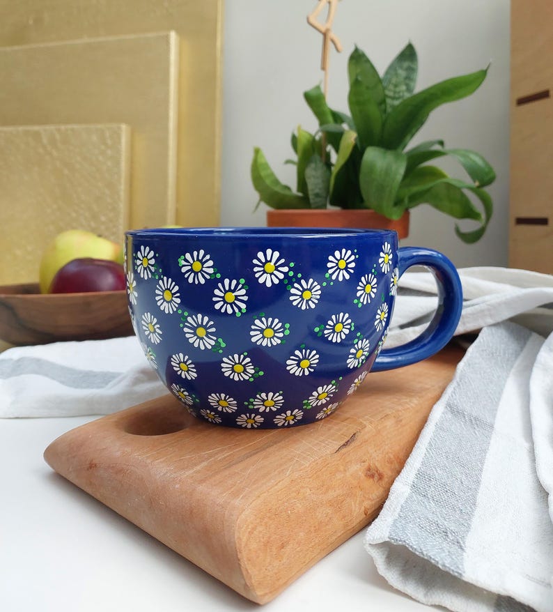 Daisy mug displayed on a wooden cutting board, showing the handle and daisy pattern