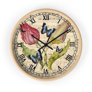 Puede incluir: Un reloj redondo con números romanos y un fondo de partitura musical. La esfera del reloj presenta un diseño floral con tulipanes rosas y amarillos y mariposas azules.