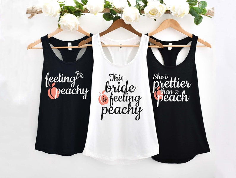 May include: Three tank tops with peach and diamond graphics and text that reads "feeling peachy", "This bride is feeling peachy", and "She is prettier than a peach".