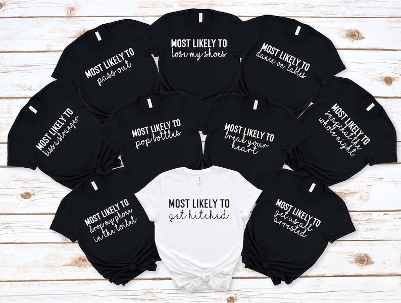 May include: Nine black t-shirts with white text that says "Most Likely To" followed by a different phrase on each shirt. One white t-shirt with black text that says "Most Likely To get hitched".