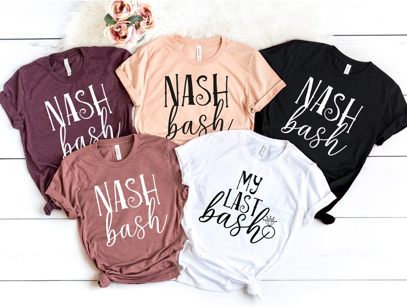 May include: Five t-shirts in shades of burgundy, peach, rose, black, and white. Each shirt displays the text "NASH bash" in a cursive font, except for the white shirt, which reads "MY LAST bash" with a diamond ring graphic.