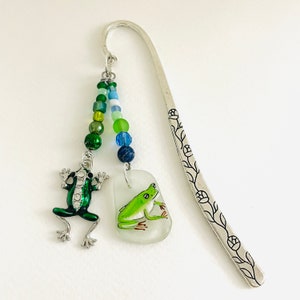 Peut inclure: Signet en argent avec un charme de grenouille verte, une grenouille verte peinte sur un charme en verre blanc et une chaîne de perles vertes, bleues et blanches.
