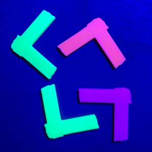 May include: Four plastic corner pieces in different colors: green, pink, and purple. The corner pieces are arranged in a star shape on a blue background.