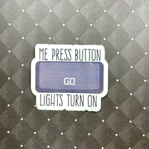 May include: White sticker with the text "ME PRESS BUTTON" above a blue button with the text "GO" and the text "LIGHTS TURN ON" below the button.
