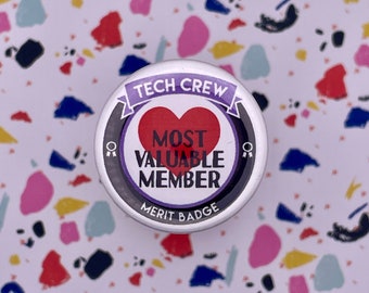 Könnte beinhalten: Ein silberner Knopf mit einem violetten Band und einem roten Herzen, auf dem "Tech Crew Most Valuable Member Merit Badge" steht.