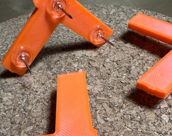 May include: Three orange plastic corner brackets with push pins. The brackets are designed to be used as corner protectors.