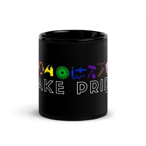 May include: Black ceramic mug with a white design that says "Make Pride" and features a rainbow of tools, including a wrench, a saw, a paintbrush, and a microphone.