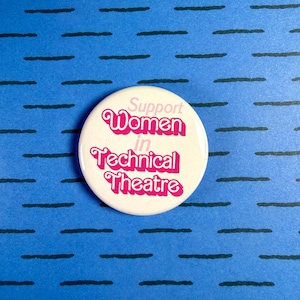 May include: A round, white button with the text "Support Women in Technical Theatre" in pink lettering. The button is set against a blue background with a pattern of black horizontal lines.