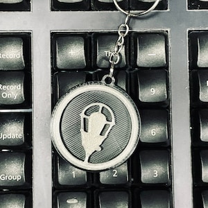 May include: A silver keychain with a black and white circular charm featuring a stylized streetlight design.