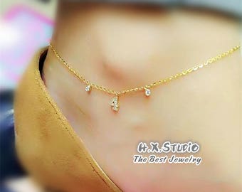 May include: A gold anklet with a small diamond charm and the number four charm. The anklet is on a person's ankle. The text "H.X. Studio The Best Jewelry" is at the bottom of the image.