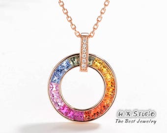 May include: A rose gold necklace with a rainbow sapphire circle pendant. The pendant is set with small square-shaped sapphires in a rainbow of colors, with a row of small diamonds down the center.